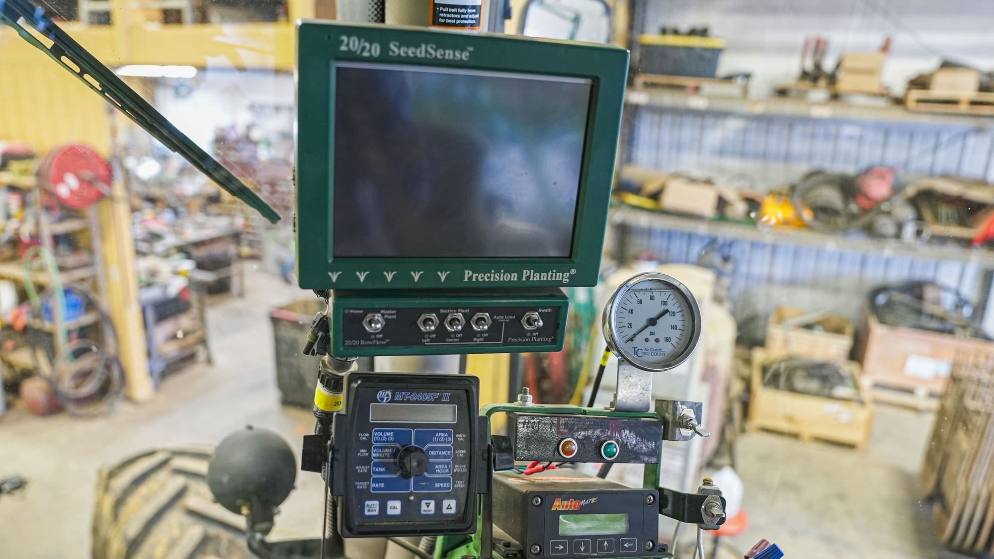 Monitor de plantio da Precision Planting montado num painel, numa oficina.
