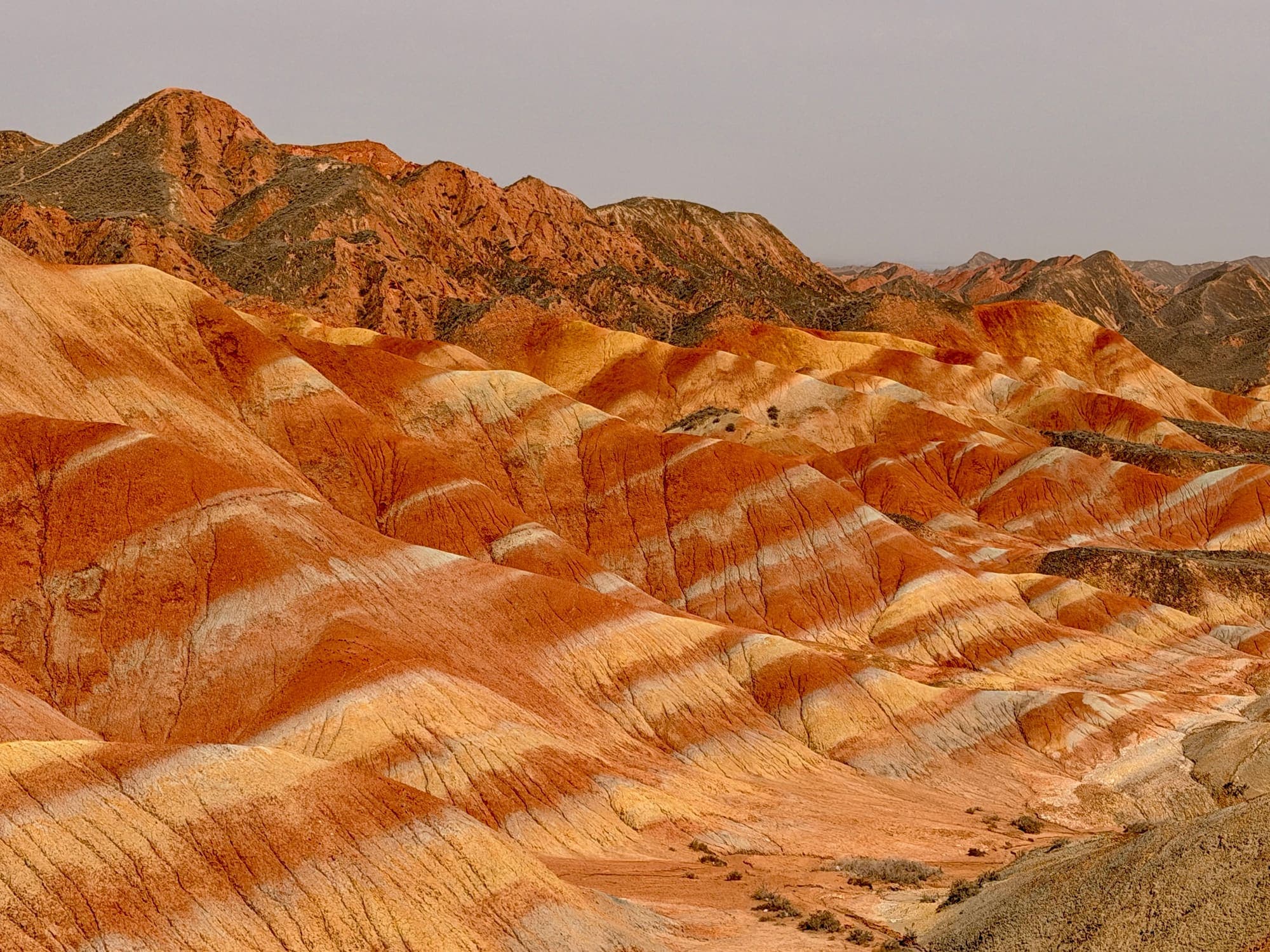 Morros em camadas de vermelho e laranja intensos no geoparque de Zhangye.