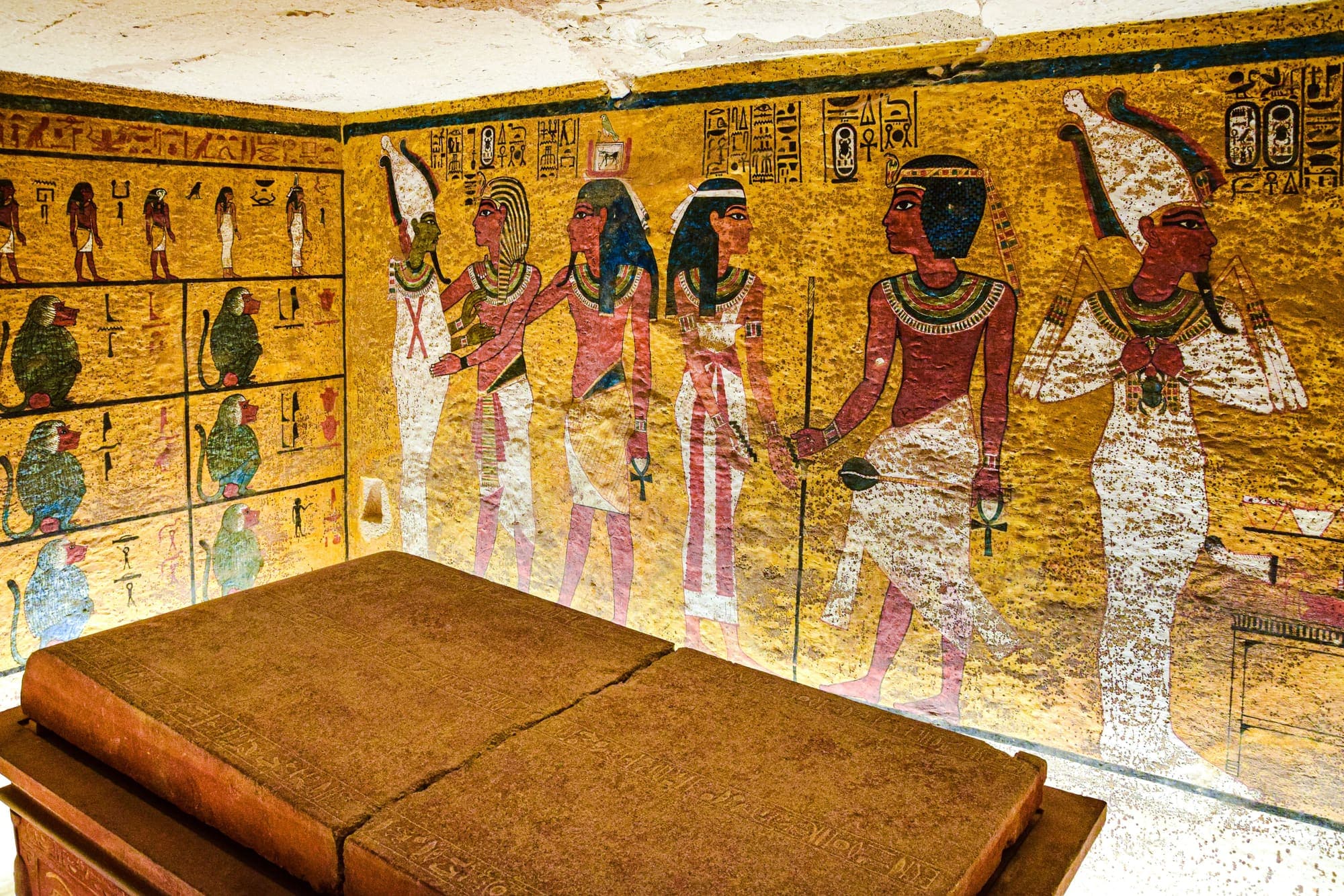 A câmara da tumba de Tutancâmon, no Vale dos Reis, com as paredes pintadas de deuses e hieróglifos e o sarcófago de pedra.