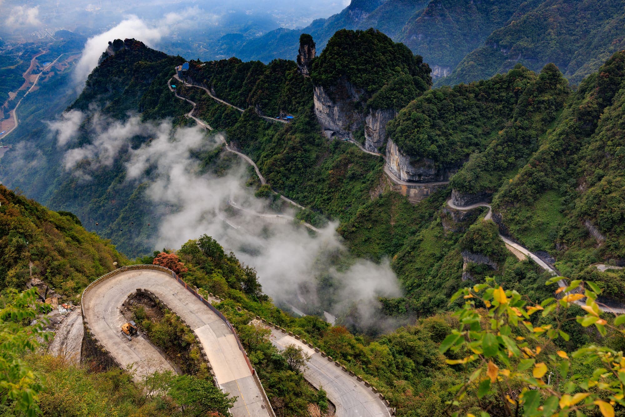 A estrada em curvas que sobe o Monte Tianmen, em Zhangjiajie, entre penhascos e nuvens baixas.