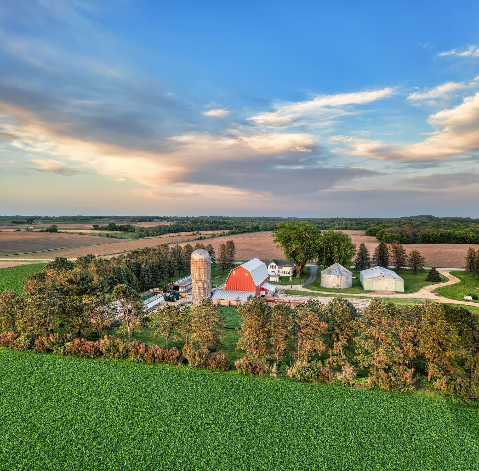 Vista aérea de uma fazenda em Minnesota, com celeiro vermelho, silos e lavouras em volta.