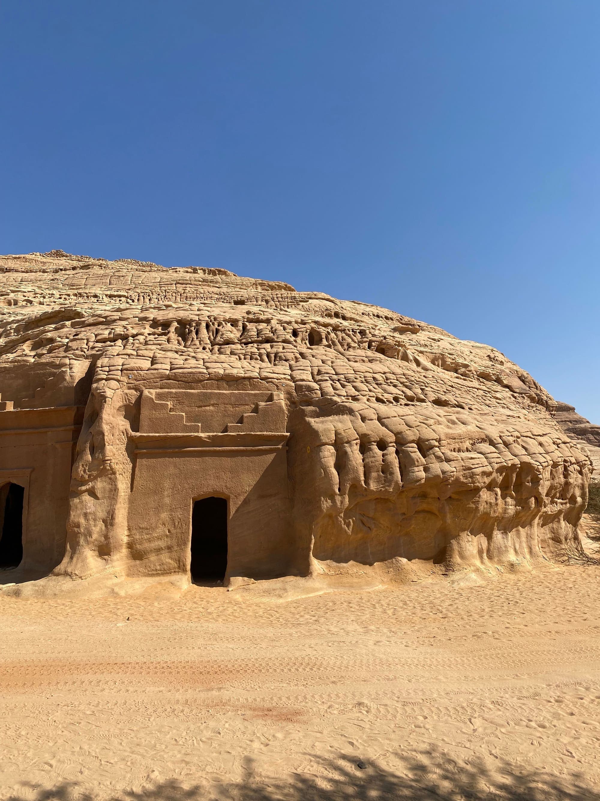 Túmulo nabateu escavado na rocha em Hegra, Al Ula, com a fachada em degraus esculpida num paredão de arenito.