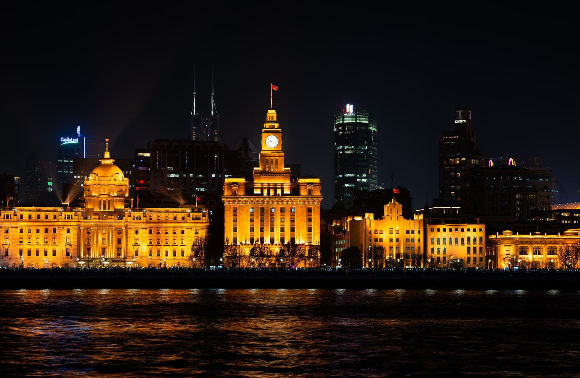 Os prédios históricos do Bund, em Xangai, iluminados à noite à beira do Rio Huangpu.